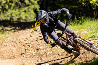 A mountain biker riding around a corner on a gravel path.